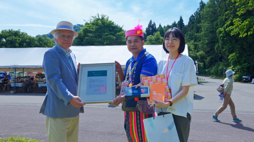 有限責任台東縣東海岸原住民社區合作社的林宋博芳理事主席代表工藝中心致贈感謝狀予日本福島縣三島町矢澤源成町長,並進行臺灣原住民祈福祝禱儀式。(圖/工藝中心提供)