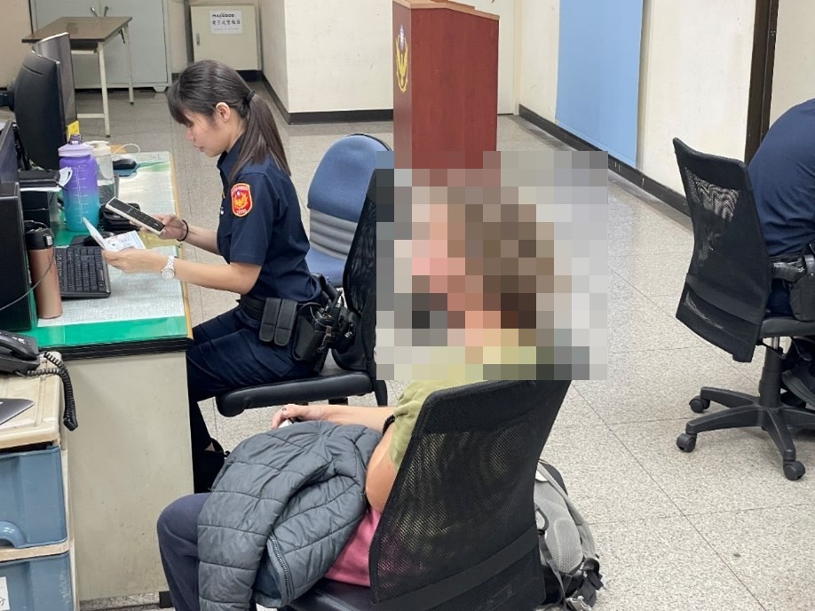 北投分局長安派出所警員陳思妤比手劃腳與遺失背包的奧地利籍遊客溝通。(記者薛秀蓮翻攝)