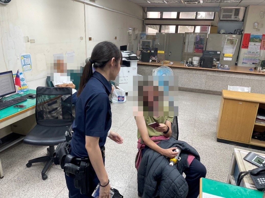 北投分局長安派出所警員陳思妤比手劃腳與遺失背包的奧地利籍遊客溝通。(記者薛秀蓮翻攝)