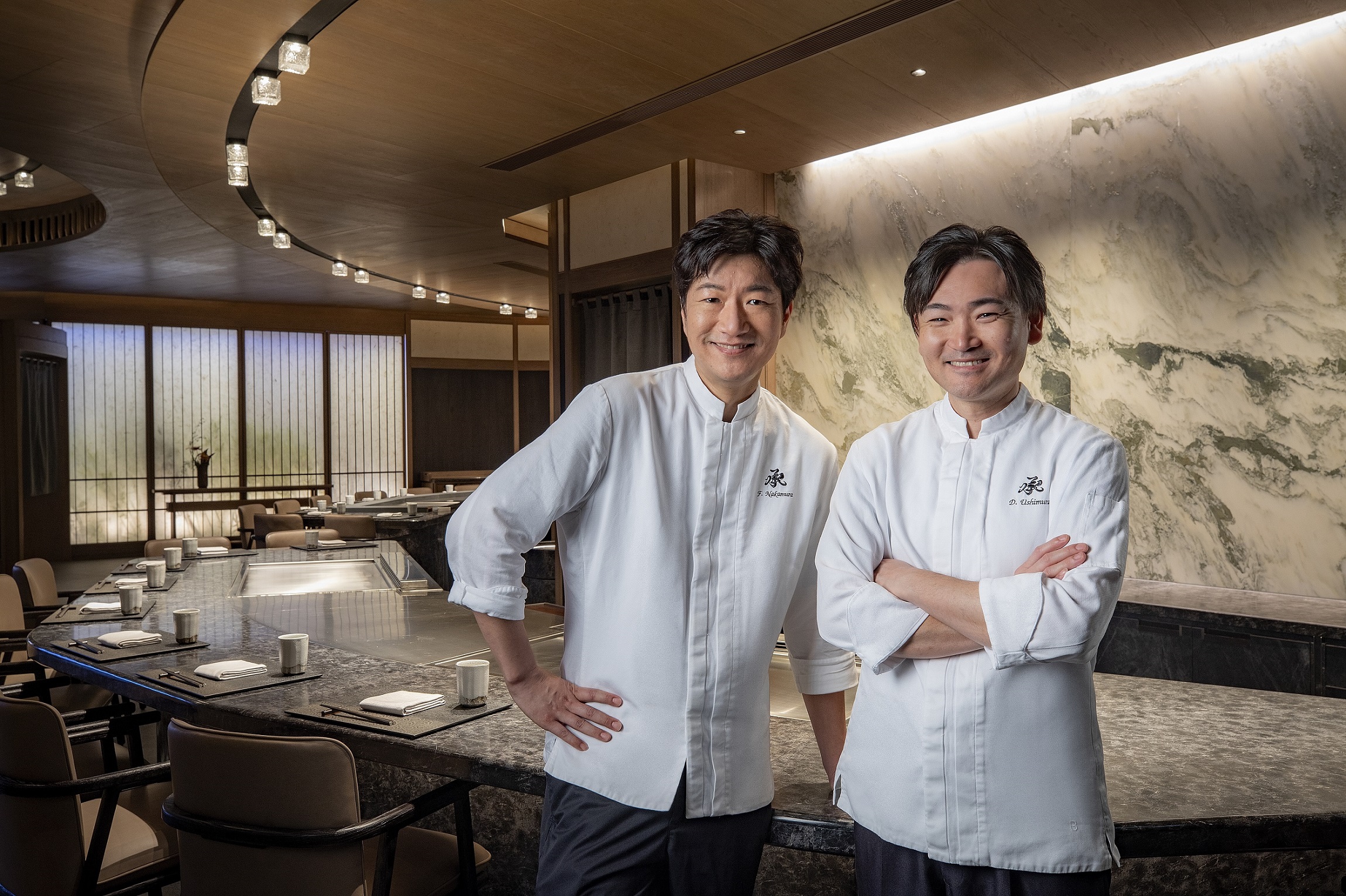 「承 · 鐵板料理」廚師長中村文則（左）、副廚牛村大介（右）領銜一群資深的高端餐飲職人，憑藉著深厚的資歷和卓越的技藝，為食客呈現活色生香的美食盛宴。