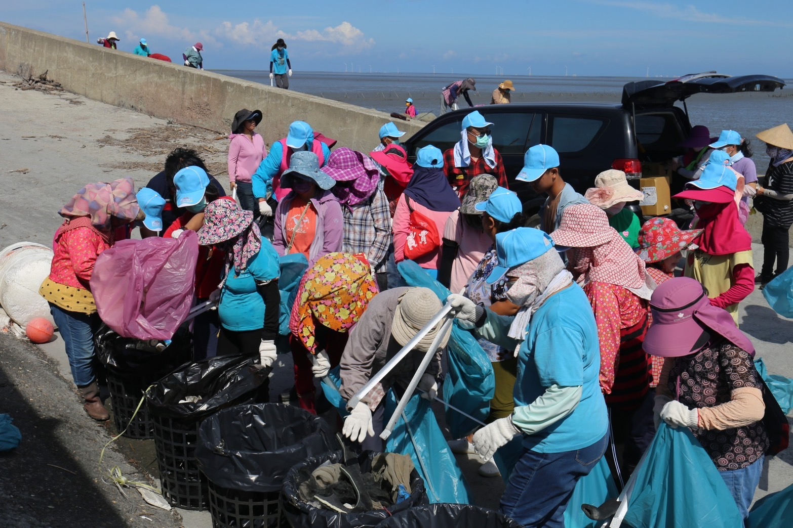 ▲大城鄉鄉公所號召社區民眾志工頂著大太陽，沿著海堤道路撿拾卡在海岸消波塊的廢棄物。（記者張溎壕攝）