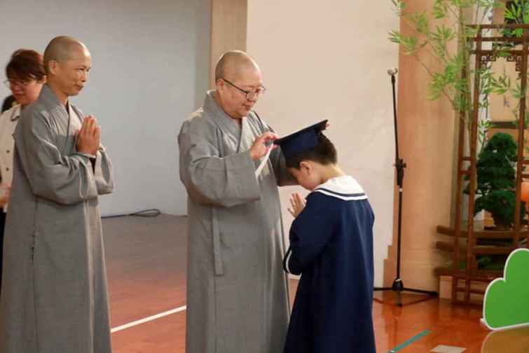 ▲靜思精舍德旭師父（右）、德守師父（左）為畢業生吳宸賓撥穗、頒畢業證書。（台中慈濟醫院提供）