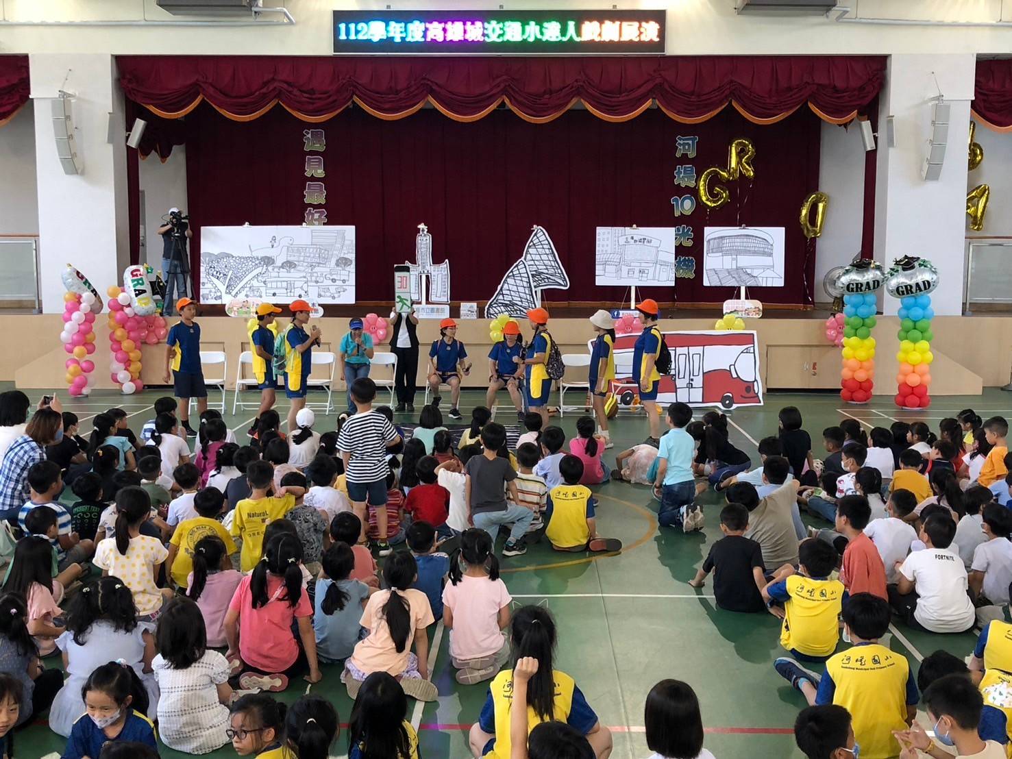 ▲校方《高雄城交通小達人》繪本變行動劇演出時，邀請兩位僑生擔任臨時演員。（記者吳月惠翻攝）