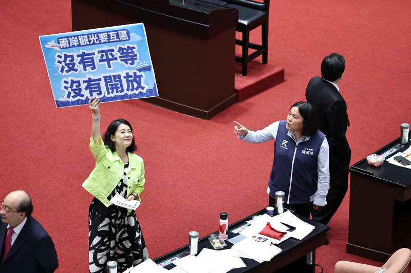 立法院會16日下午針對國民黨團提議解除「赴中觀光禁團令」等案進行表決。民進黨立委吳思瑤(綠衣者)高舉手牌,與國民黨立委陳玉珍(前右)在議場內互相表達立場。圖/中央社