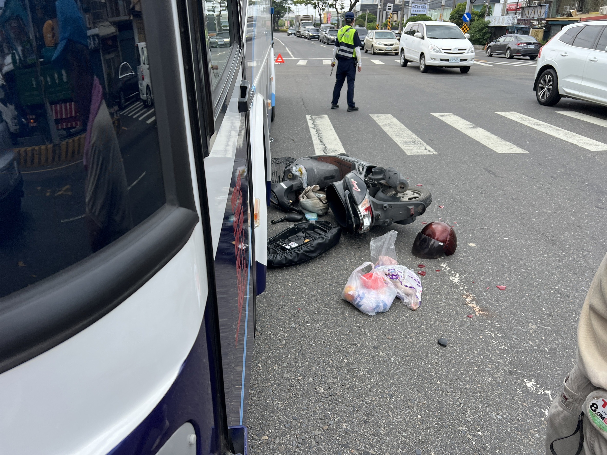 ▲花壇鄉中山路發生起1起驚險車禍，騎機車婦人擦撞公車後人車倒地，機車稀爛，機車上載運的蔬菜與物品散落一地，婦人幸運僅受輕傷。（民眾提供）