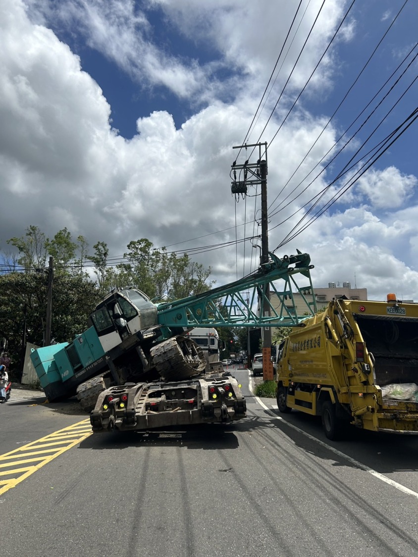 拖板車駕駛陳姓男子(41歲)駕駛拖板車行經粉寮路二段8號前轉彎處時,拖板車上所載吊車滑落至道路,導致交通堵塞。(記者黃荷琇 翻攝)