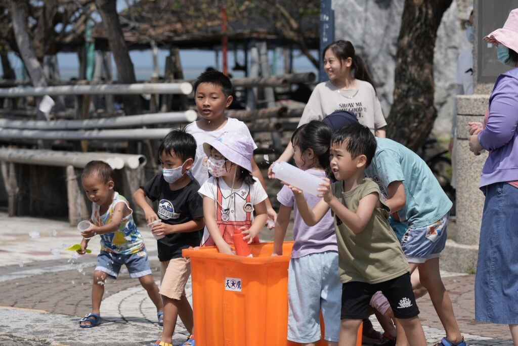 ▲小朋友爭先恐後的伸手進入桶子裡面,拿起桶內的水球及碎冰開始找目標攻擊。(屏東縣政府提供)