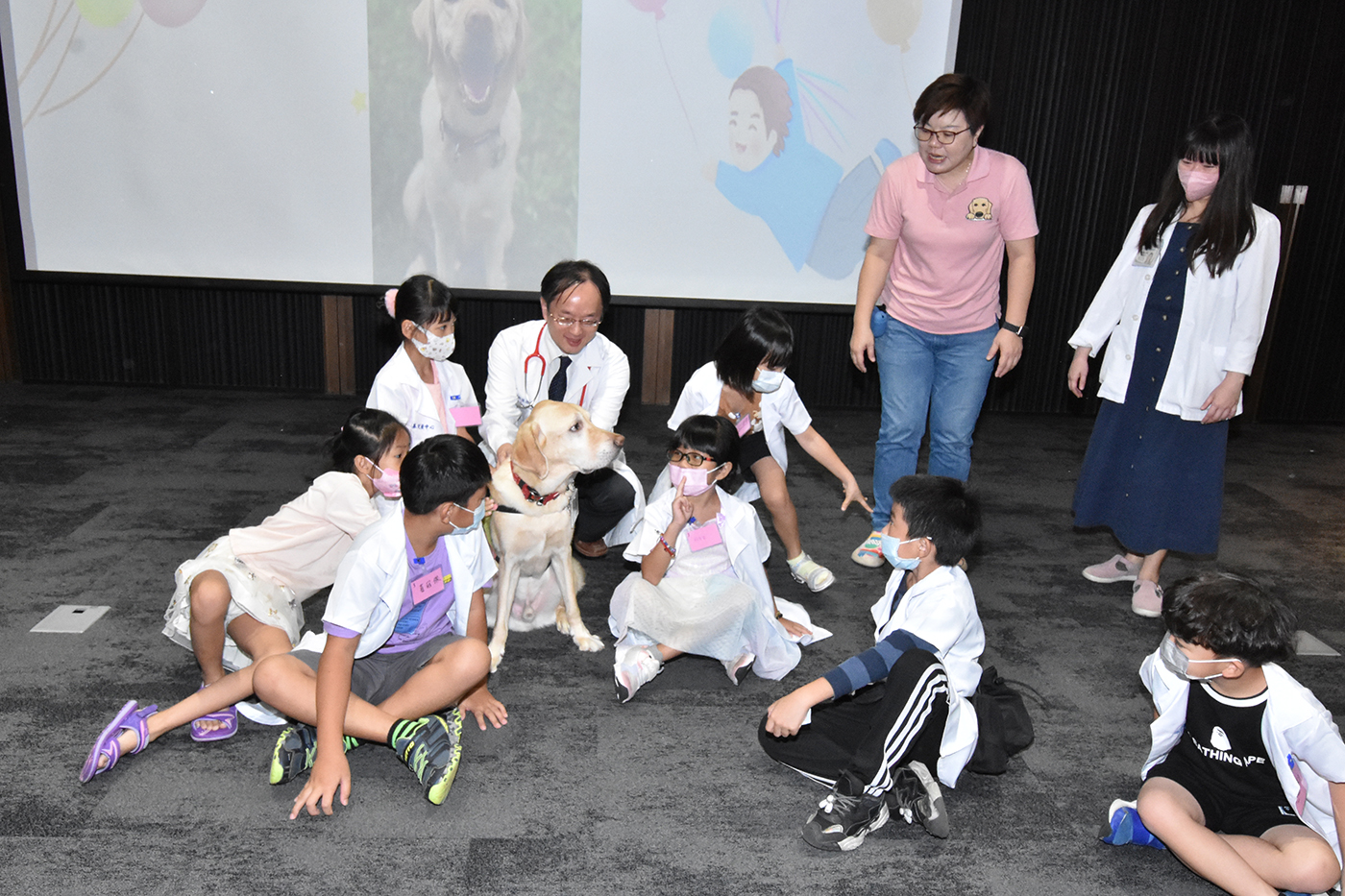 ▲亞瑟狗狗媽媽（右二）介紹醫療犬的功能，讓小朋友和亞瑟互動。（記者張溎壕攝）