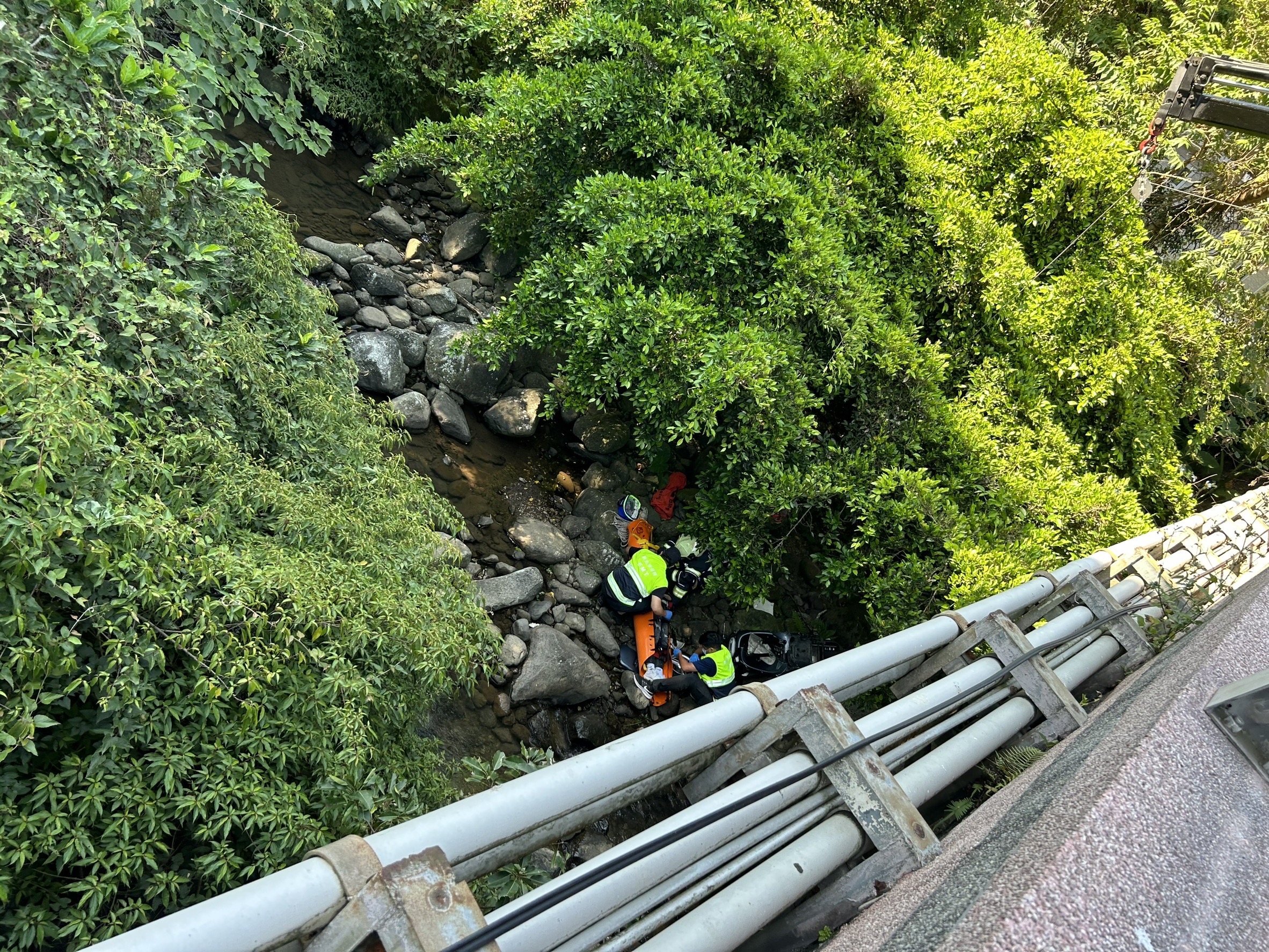 ▲新北市三芝區北新路,有民眾自撞後翻越龜仔山橋護欄墜落溪谷。(翻攝畫面)