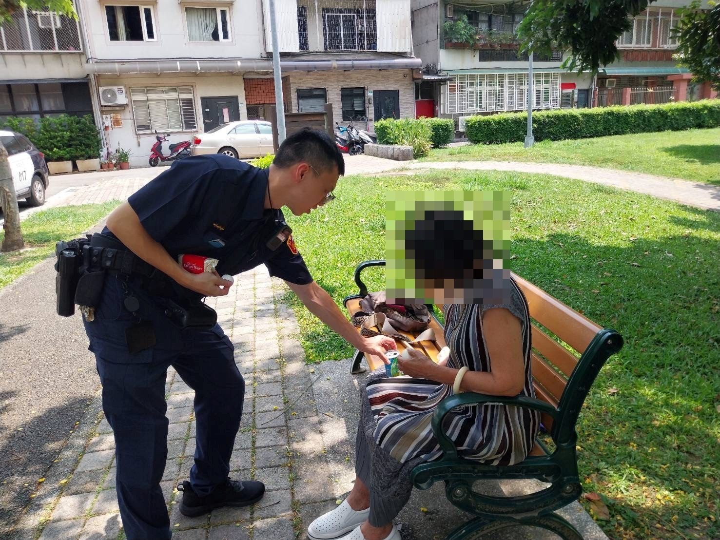 老婦疑似中暑坐在公園長椅上,北投分局奇岩派出所警員蔡皇賜 協助聯繫家屬到場。(記者薛秀蓮翻攝)