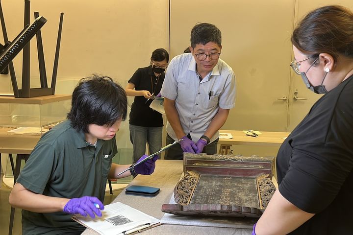 ▲何金樑主任(中)與民博奈良雅史副教授(左)進行客發中心館藏客家家族神牌位點驗。 圖:客家委員會客家文化發展中心/提供