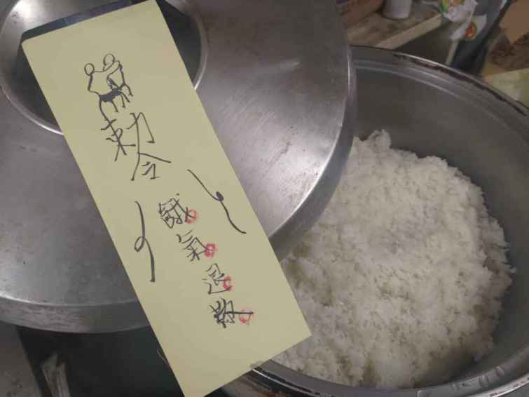 ▲飯鍋上亦有「餓氣退散」趣味符咒，盼助寒士不要挨餓、身體永保健康，重建人生道路平安順利。（人安基金會彰化平安站提供）