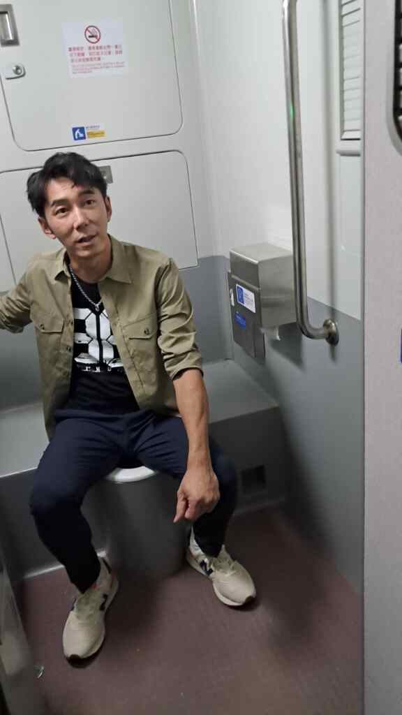▲李李仁坐在仿高鐵車廂廁所，講解拍攝過程。（楊小雯拍攝）