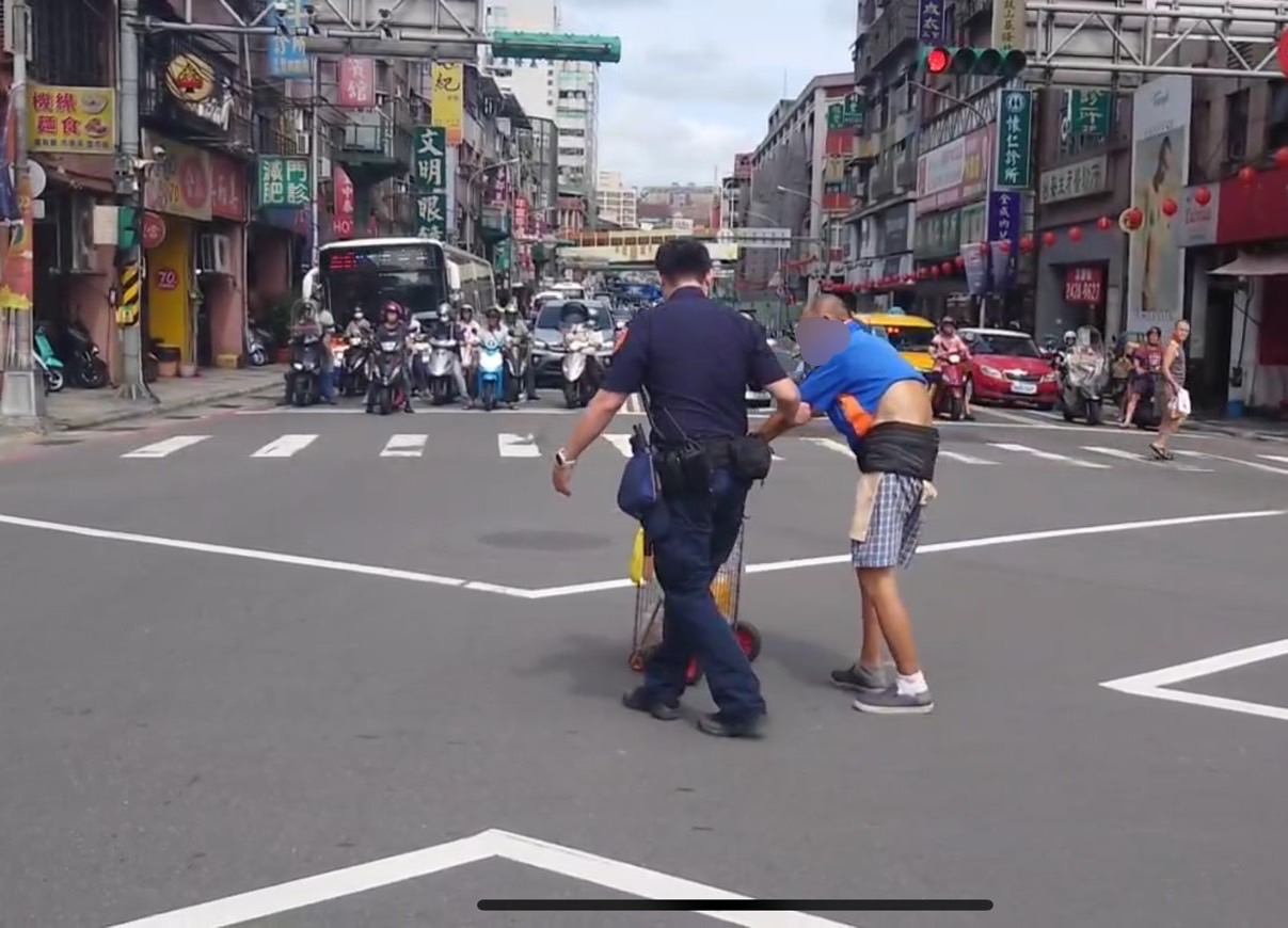 警方協助老翁過馬路。（記者薛秀蓮翻攝)