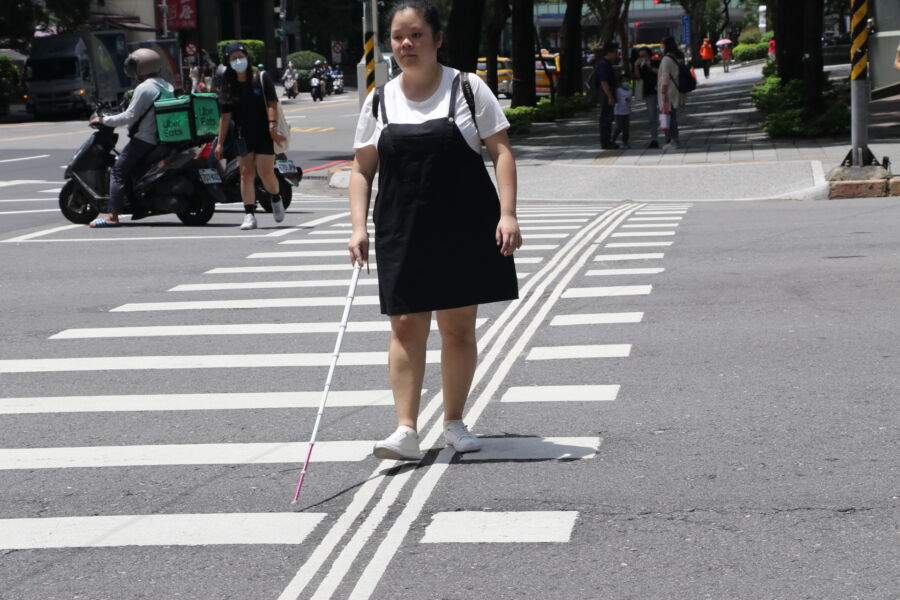 圖/視障者施芸婷在通過十字路口時走「導盲行穿線」,認為更有所依循、也更安全。(新北市政府社會局提供)