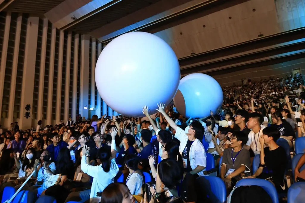 東海大學為了讓AI世代感受不一樣的大學之夜,校長張國恩還率領行政團隊在晚會中大跳時下流行舞蹈《晚安大小姐》,更融入「排球少年」元素,讓三千位學生一起打超大型排球。(圖/東海大學提供)