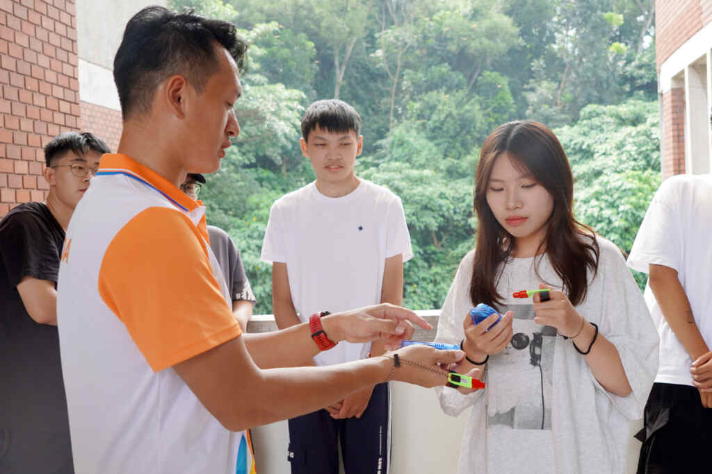 ▲彰化縣體育會定向越野委員會總幹事游為楷(左)向大葉大學學生介紹比賽打卡用的設備。（記者林明佑翻攝）