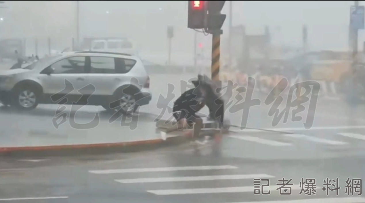 ▲高雄少年拚盡全力過馬路仍不敵強風。(圖/民眾提供)