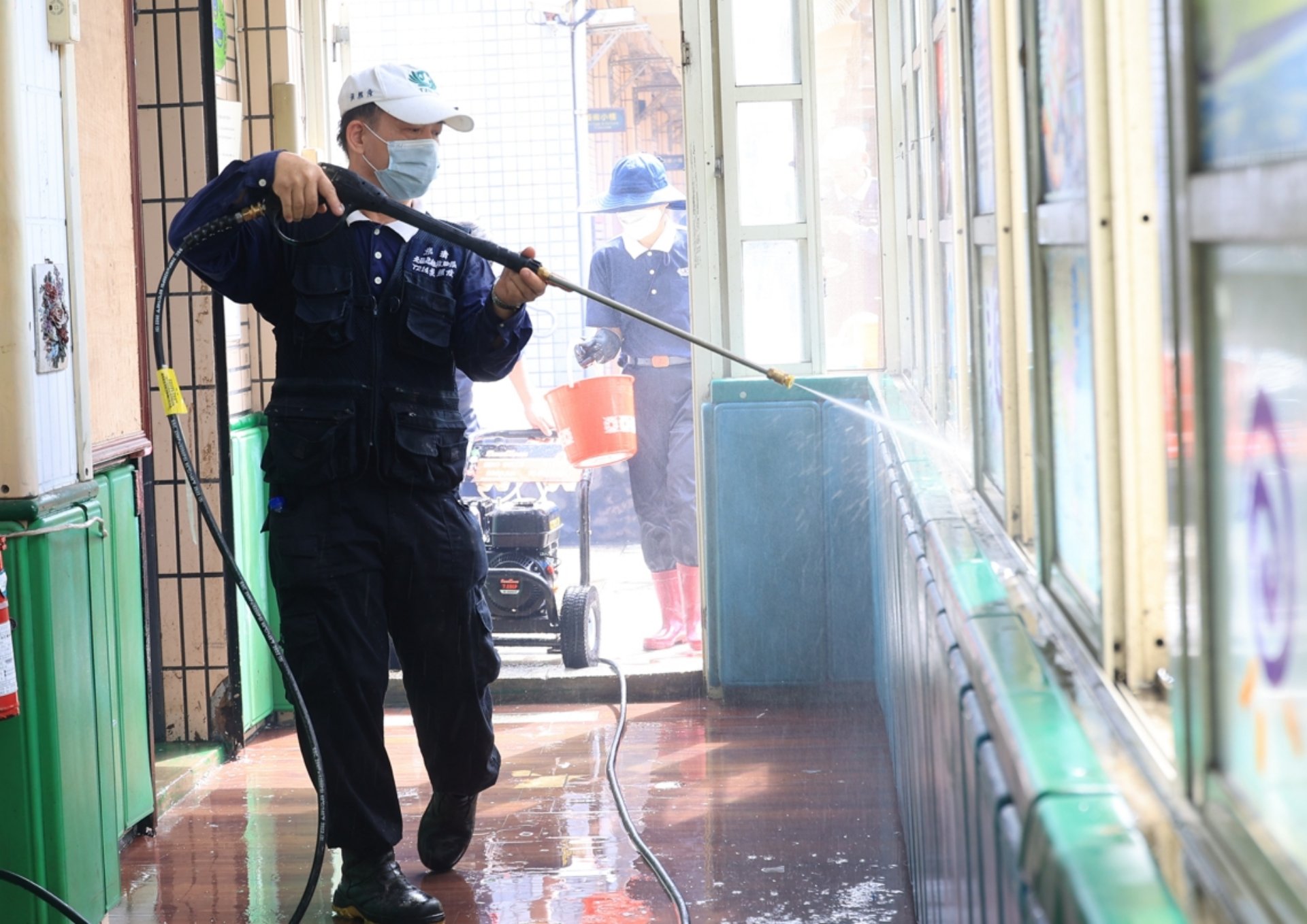 走道上、花臺邊，有些淤泥被太陽照得乾涸了，男眾志工就立即搬來高壓沖水機，以強力水柱沖洗。