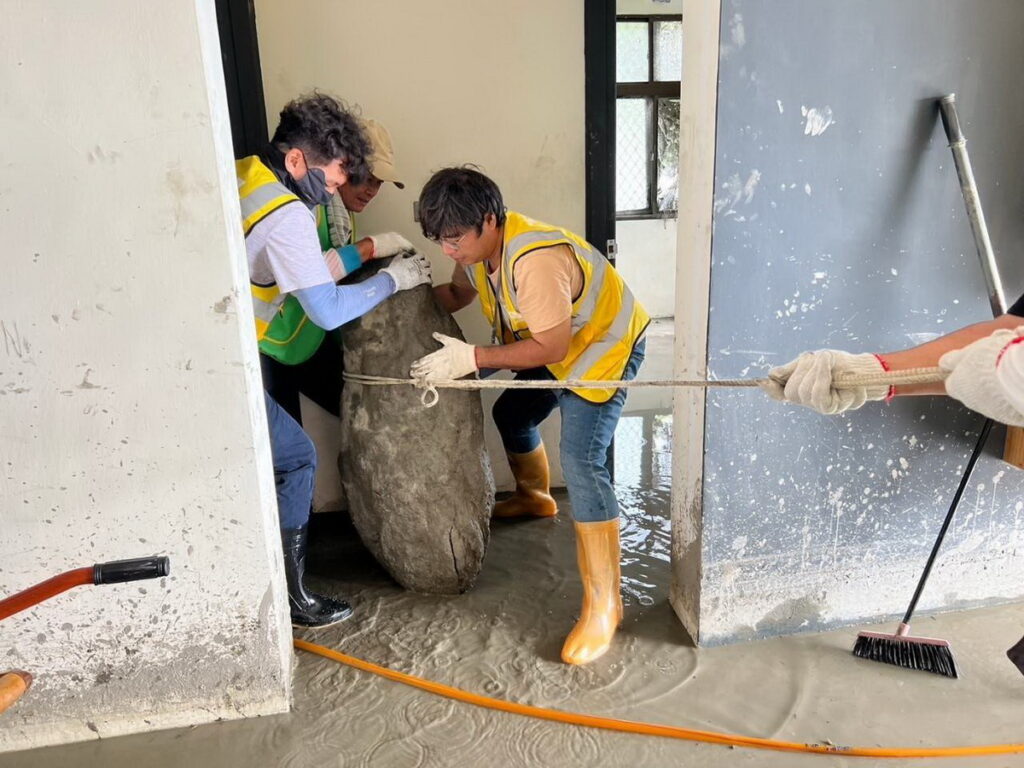 芥菜種會以工帶振團隊合力把陳太太家中巨石搬出,並利用高壓清洗機,清除淤泥,協助家園復原。(芥菜種會提供)