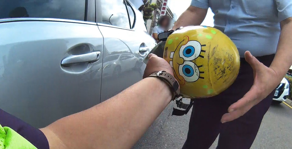 ▲圖說:員警伸手略施巧勁後,竟成功取出卡在車輛底盤下的「海綿寶寶」安全帽 (圖/台中市政府 提供)