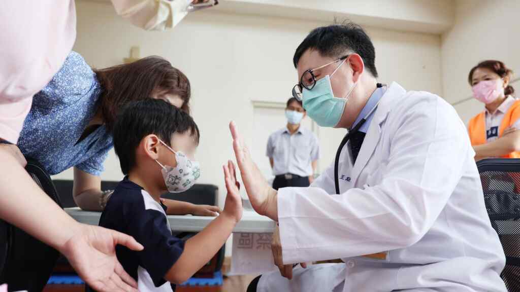 ▲宏仁醫院總院長王斯弘透過擊掌與幼童互動,免除緊張情緒。(記者林明佑翻攝)
