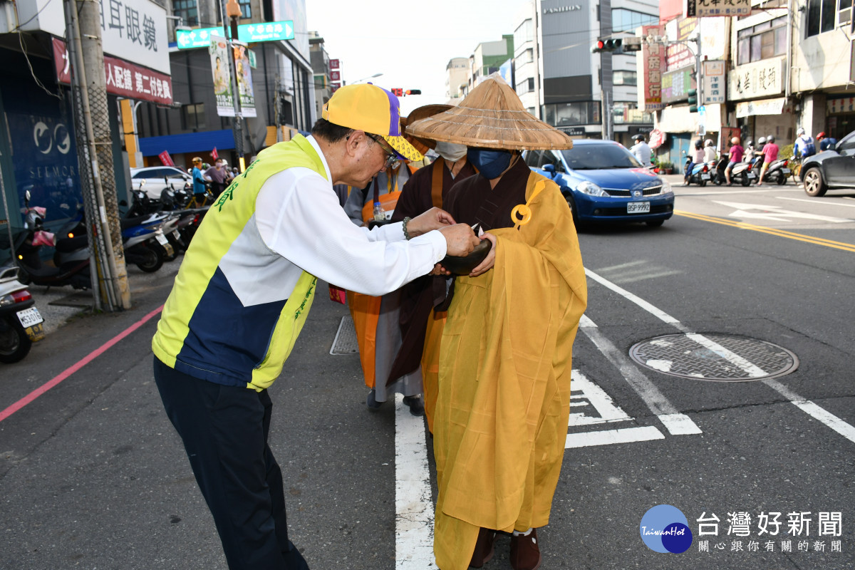 林世賢市長率先敬戲現金入化緣師父手持的缽內。圖/記者鄧富珍翻攝