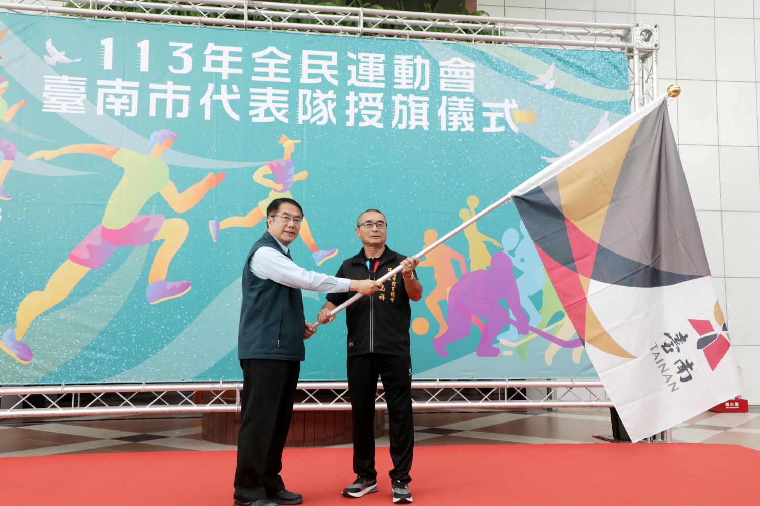 ▲市長黃偉哲為全民運台南市代表隊授旗，由體育總會理事長吳志祥代表接下。（圖／記者陳彥霖翻攝）
