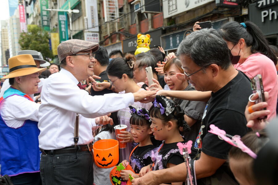 /新北市長侯友宜身著復古裝扮,帶領變裝民眾一起踩街遊行,沿路發送糖果給小朋友們。(新北市政府經發局提供)