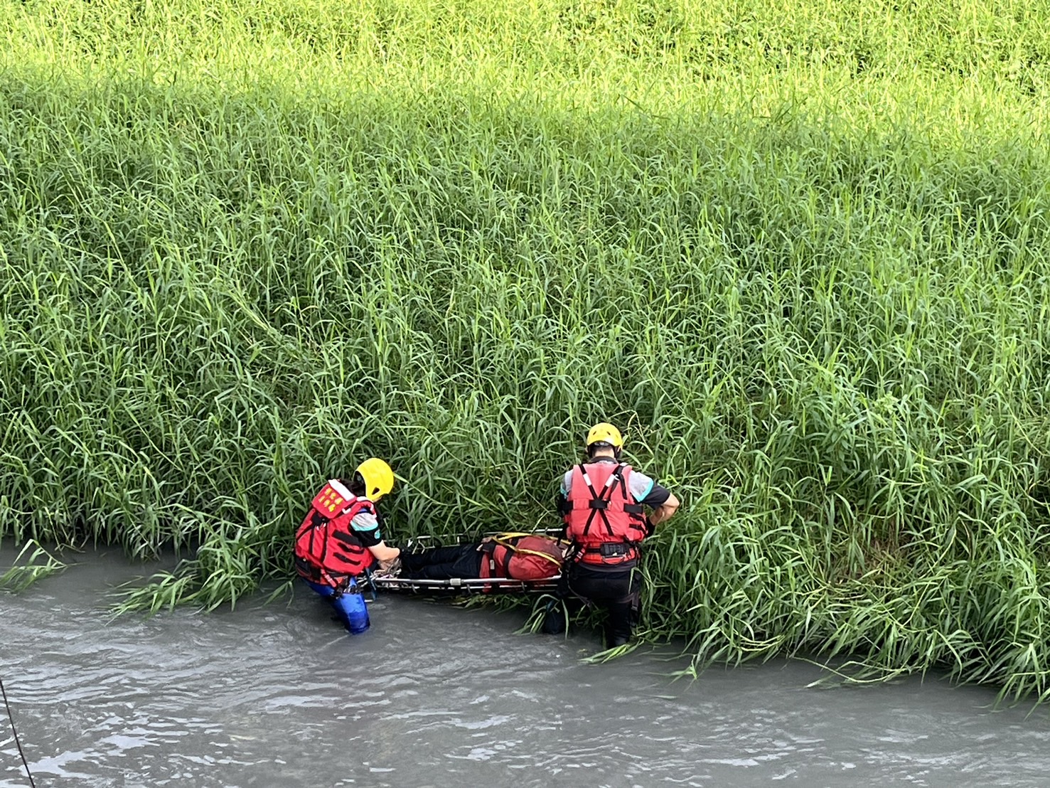 ▲員林市員林大排發生溺水事件,使用器材車將人員吊掛至員大排中進行徒手攔截,再以籃式擔架將溺者吊掛上岸後送醫。(消防局提供)