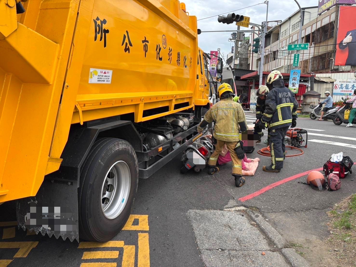 ▲彰化市中華西路與崙美路口發生一起垃圾車與機車擦撞意外，機車騎士摔倒，並被垃圾車夾住左小腿，消防人員用破壞器材搶救。（民眾提供）