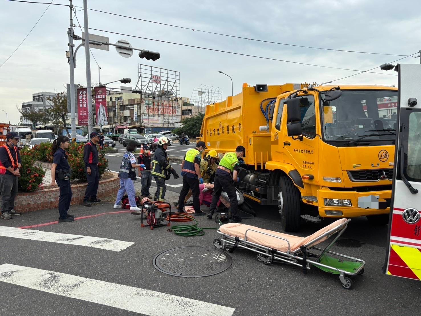 ▲彰化市中華西路與崙美路口發生一起垃圾車與機車擦撞意外，機車騎士摔倒，並被垃圾車夾住左小腿，消防人員用破壞器材搶救。（民眾提供）