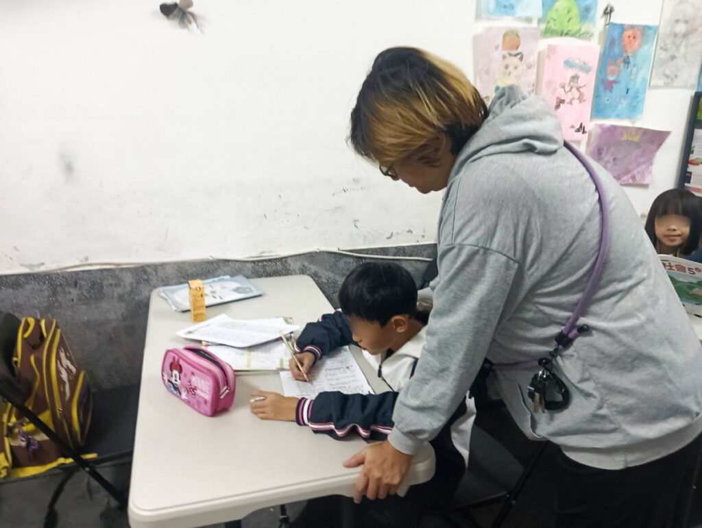 圖為小玉在社子島助人網陪讀班陪伴孩子讀書。(芥菜種會提供)