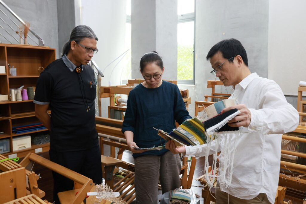 國立臺南藝術大學材質創作與設計系教授陸佳暉（中），說明該系纖維工作室教學場域及學生作品。右為該系鄭正雄主任，左為工藝中心主任陳殿禮（圖/工藝中心提供）