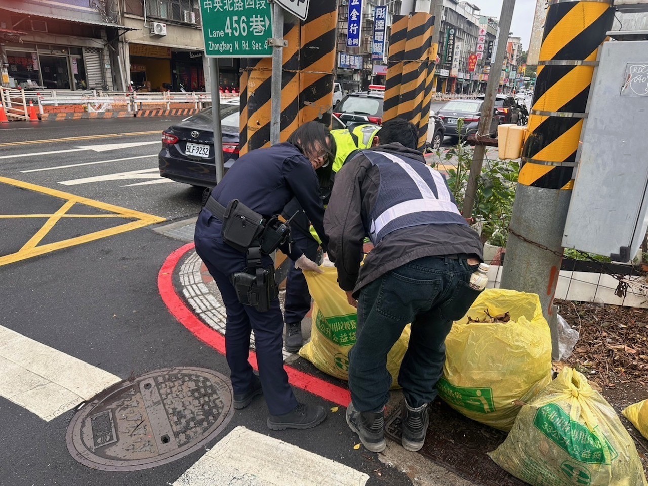 北投一名賴姓老翁不伸遺失背包，北投分局關渡所警員林泰宇、鄭伊珊陪賴翁在垃圾堆裡翻找，終於找回包包。（圖/記者薛秀蓮 翻攝）