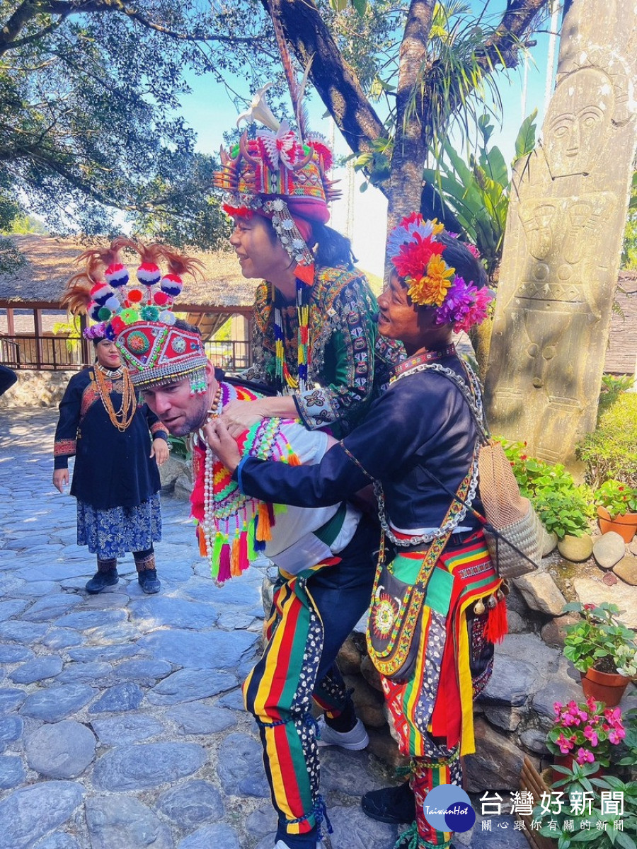 著裝參觀排灣族的貴族婚禮,並嘗試用原住民結婚揹新娘的姿勢揹起女性同伴。(九族文化村企劃部提供)