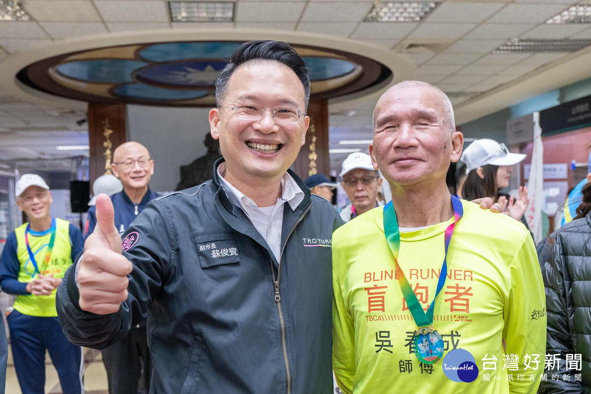 桃園市副市長蘇俊賓與盲跑者吳春成合影。<br /><br />