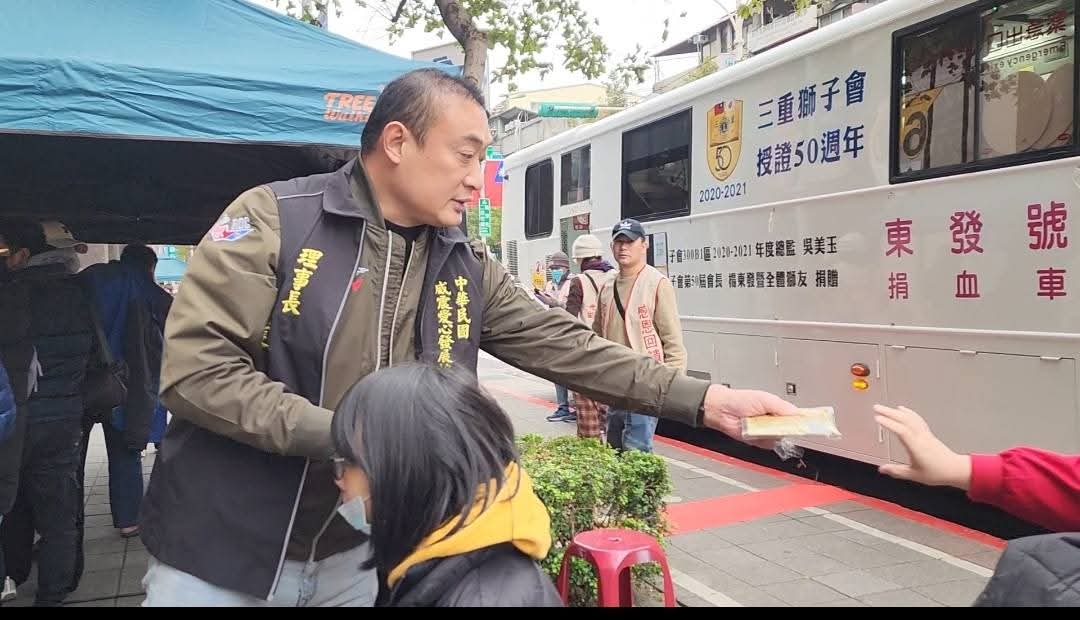 吳明達理事長親發暖暖包于寒風中等待捐血的民眾。(記者 趙靜姸翻攝)