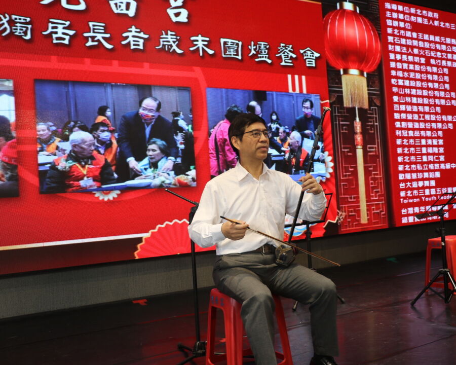 /新北市副秘書長柯慶忠應邀拉二胡娛樂獨居長輩。(新北市政府社會局提供)