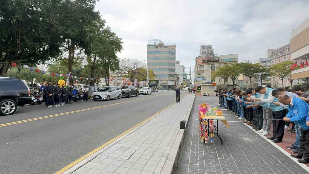 ▲靈柩起靈前往員林市公所，在公所前短暫停留，代理市長賴致富率公所一級主管與員工及各里里長列隊在公所大門前送行，員工雙手合十，鞠躬向游市長致謝，感謝游市長的指導照顧。（記者林明佑翻攝）