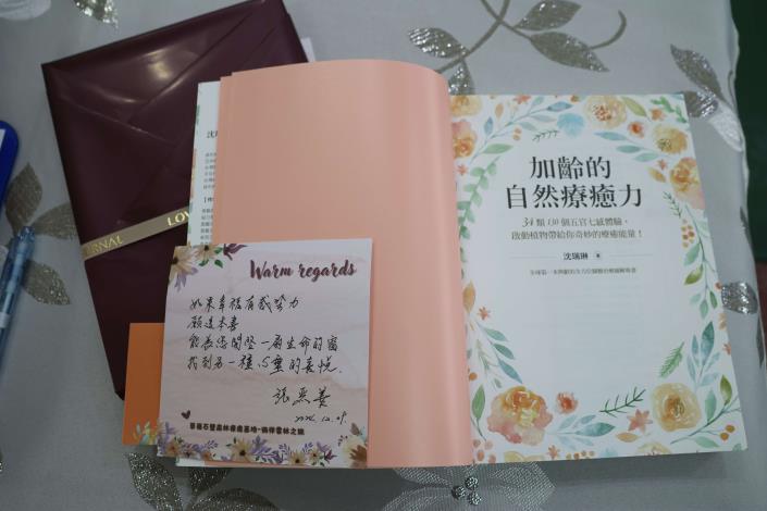 張麗善贈送《加齡的自然療癒力》一書，鼓勵女校長關愛自己，體驗自然療癒能量。(記者廖承恩翻攝)