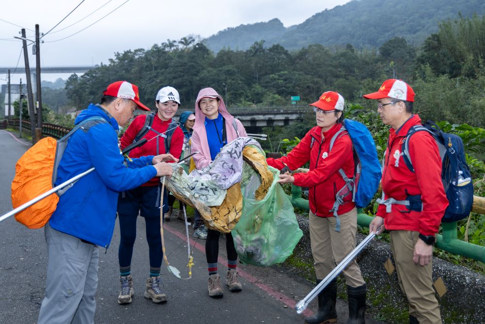 《圖說》參與民眾手持長夾與垃圾袋,沿步道拾起天燈殘骸及垃圾。〈觀旅局提供〉