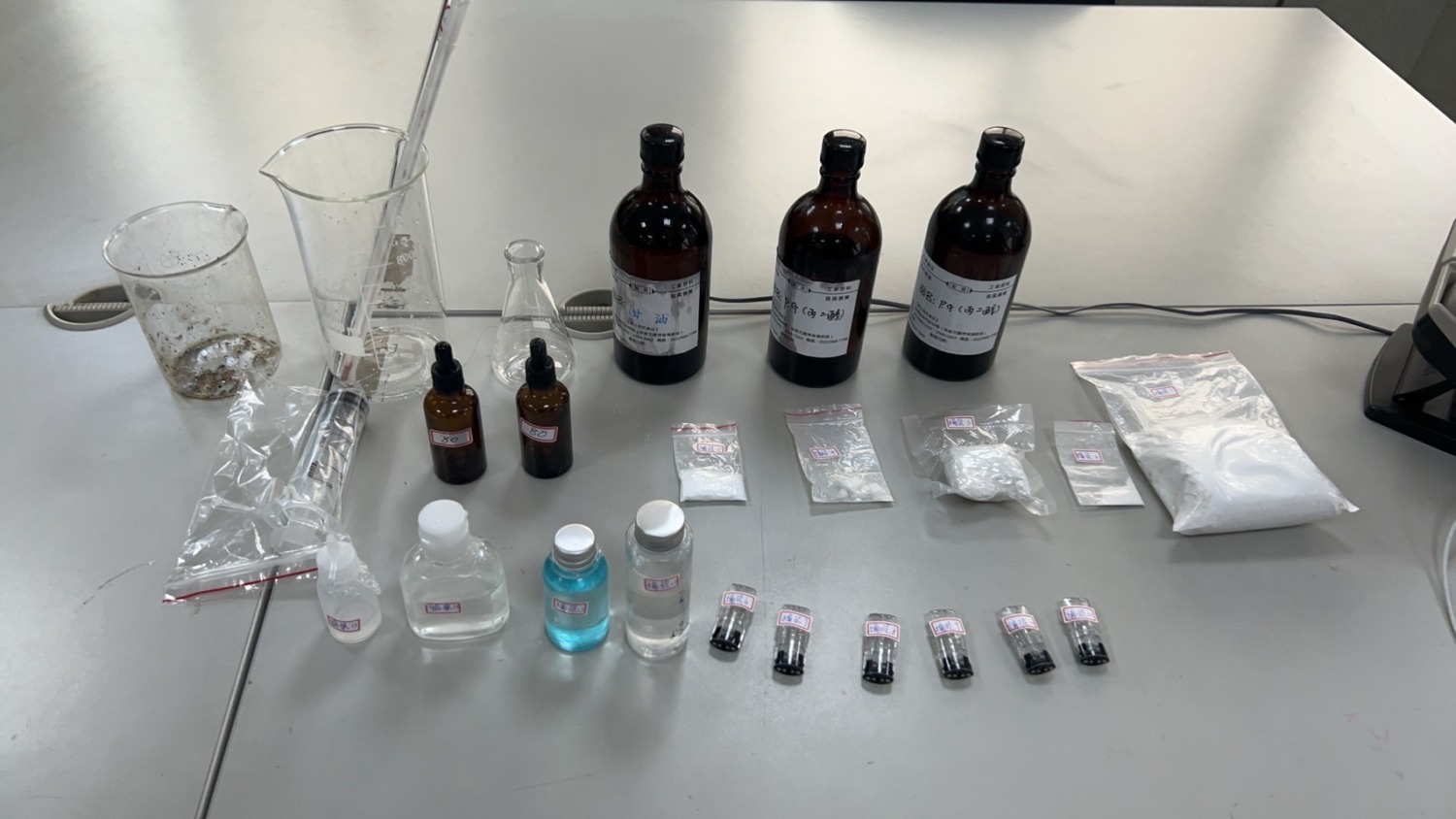 警方查扣海洛因5包、依託咪酯(喪屍藥)菸彈6顆、依託咪酯菸油4瓶及甘油、丙二醇、燒杯、溫度計、攪拌棒、注射筒等製毒設備。(記者 黃荷琇翻攝)