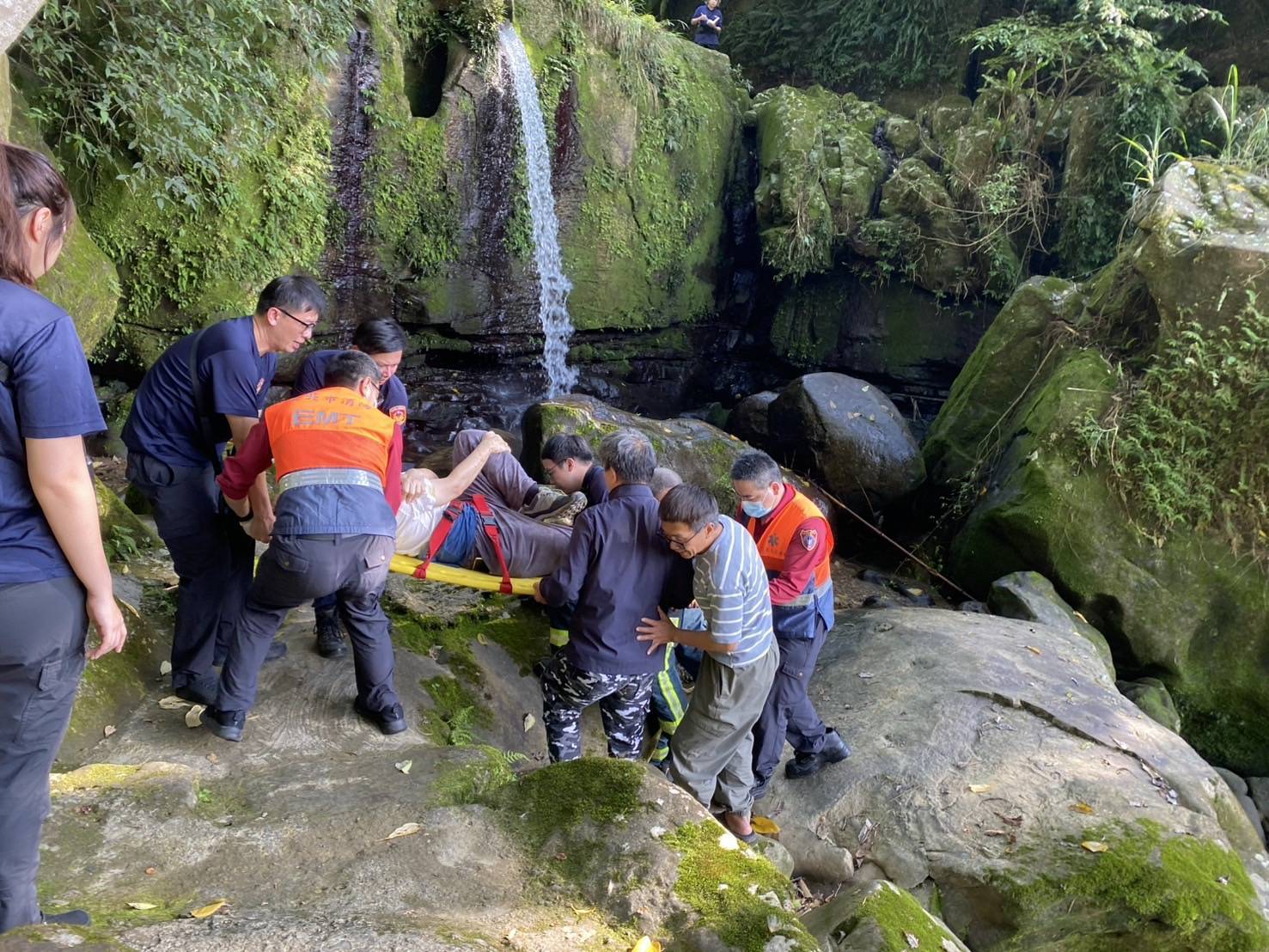 文山第一分局指南派出所警員與消防人員合力將傷者抬下山,成功化解危機。(記者 黃荷琇翻攝)
