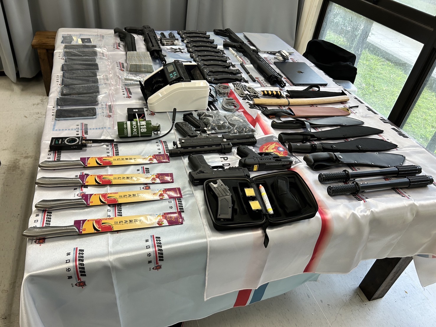 警方現場查扣大量不法所得與犯罪工具外,現場還發現鎮暴槍、模擬槍及各類刀械。(記者 黃荷琇翻攝)