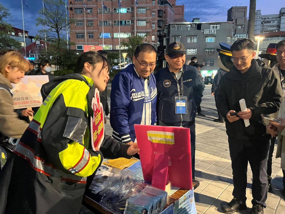 《圖說》侯友宜在識詐攤位聆聽女警宣導最新的百斬計畫，並參與按讚活動、右二警察局長廖訓誠、右一新莊分局長陳保緒。〈新莊分局提供〉