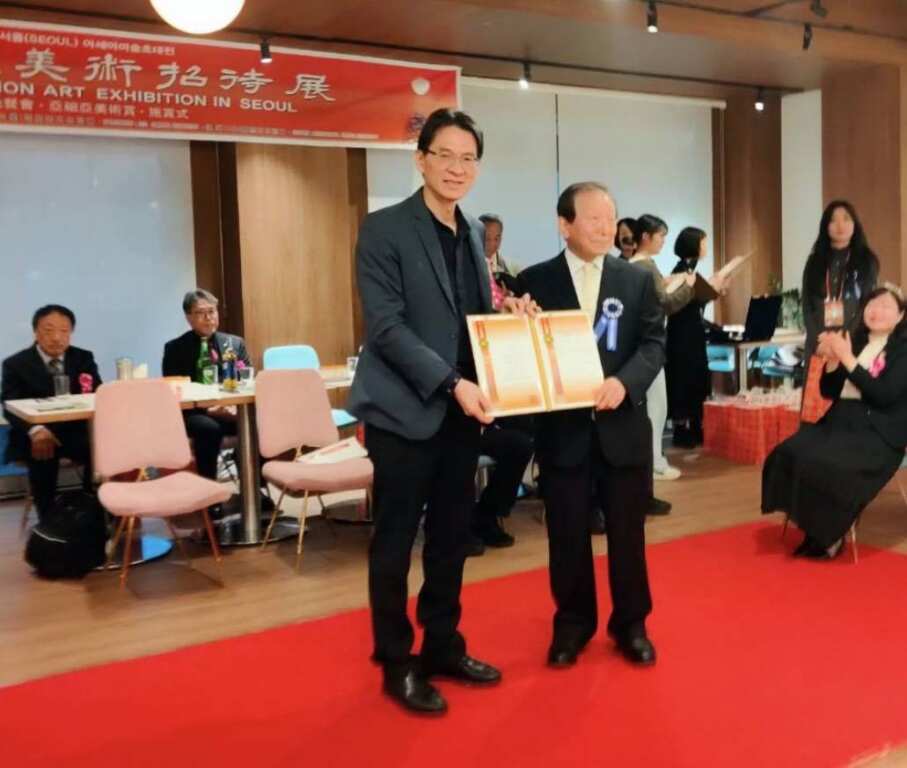 ▲韓國文化藝術研究會會長姜信雄於韓國首爾亞細亞藝術展開開幕式現場頒贈「特別貢獻狀」給林家同總院長。（記者林明佑翻攝）