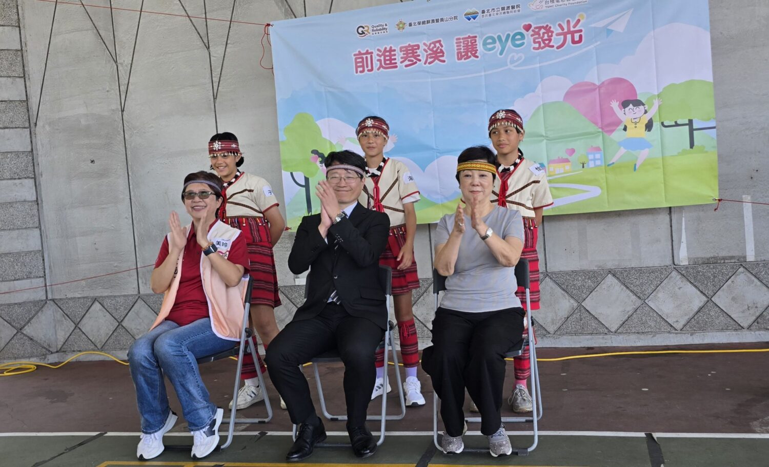 寒溪國小學童幫張淑芬董事長(右) 北榮員山分院熊夢平院長(中) QR組織陳美玲副處長戴上象徵泰雅族祖靈眼睛的頭帶。 (台積電慈善基金會 提供)