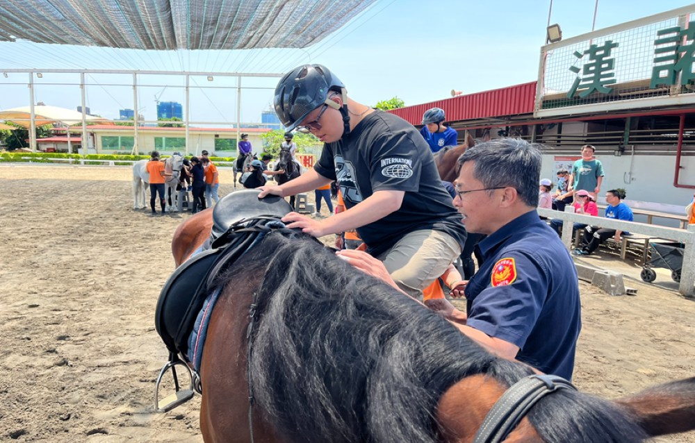 近距離接觸體驗馬術 折翼天使驚喜燦笑 2 《圖說》騎警隊員幫助障友騎乘馬匹。〈警察局提供〉