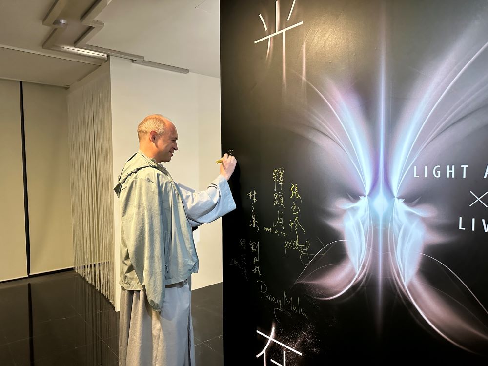 《圖說》呂天恩神父在「光在萬物」特展展板上簽名。〈宗博館提供〉
